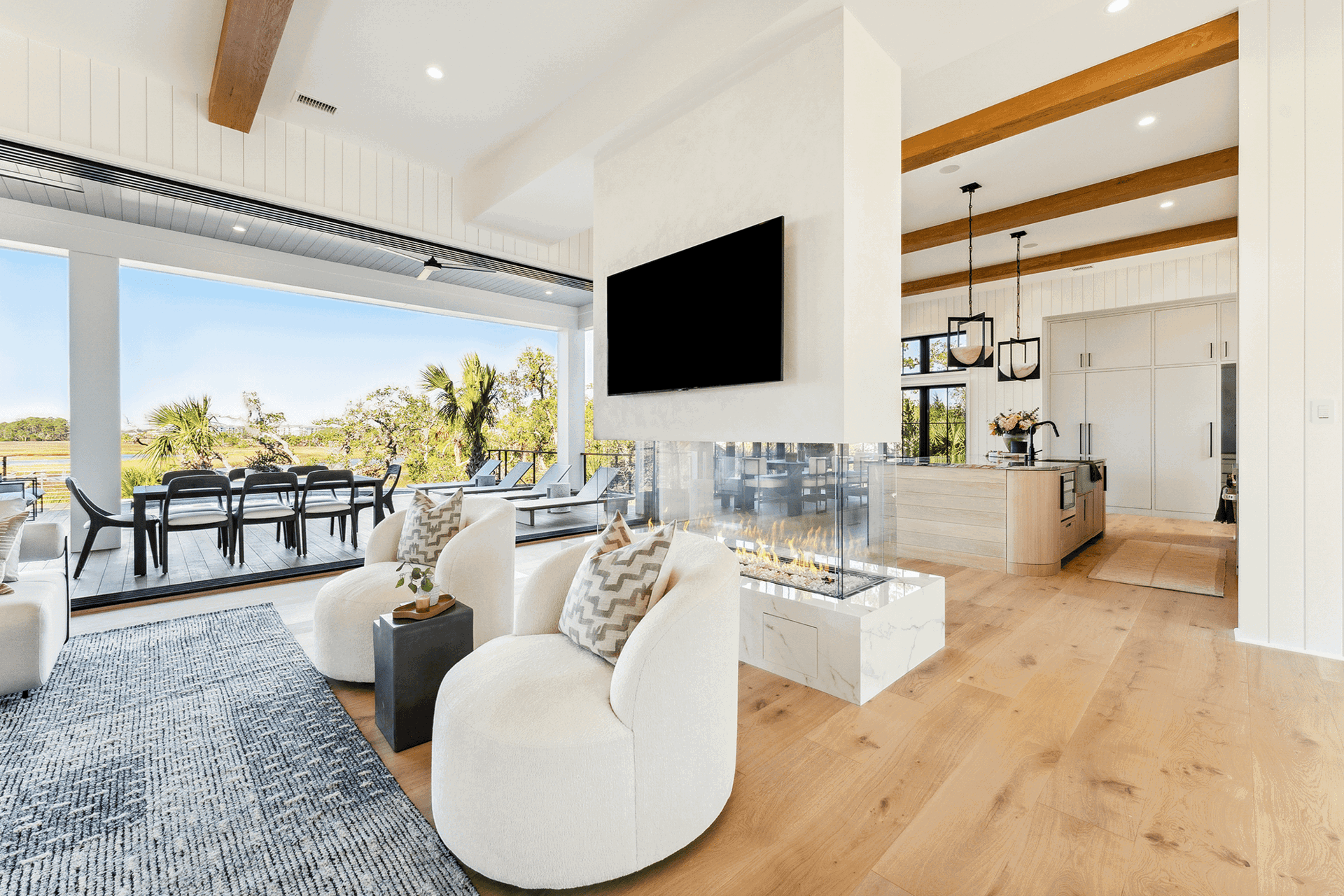 Open-concept living room with large sliding glass doors creating seamless indoor-outdoor flow to a covered dining space.