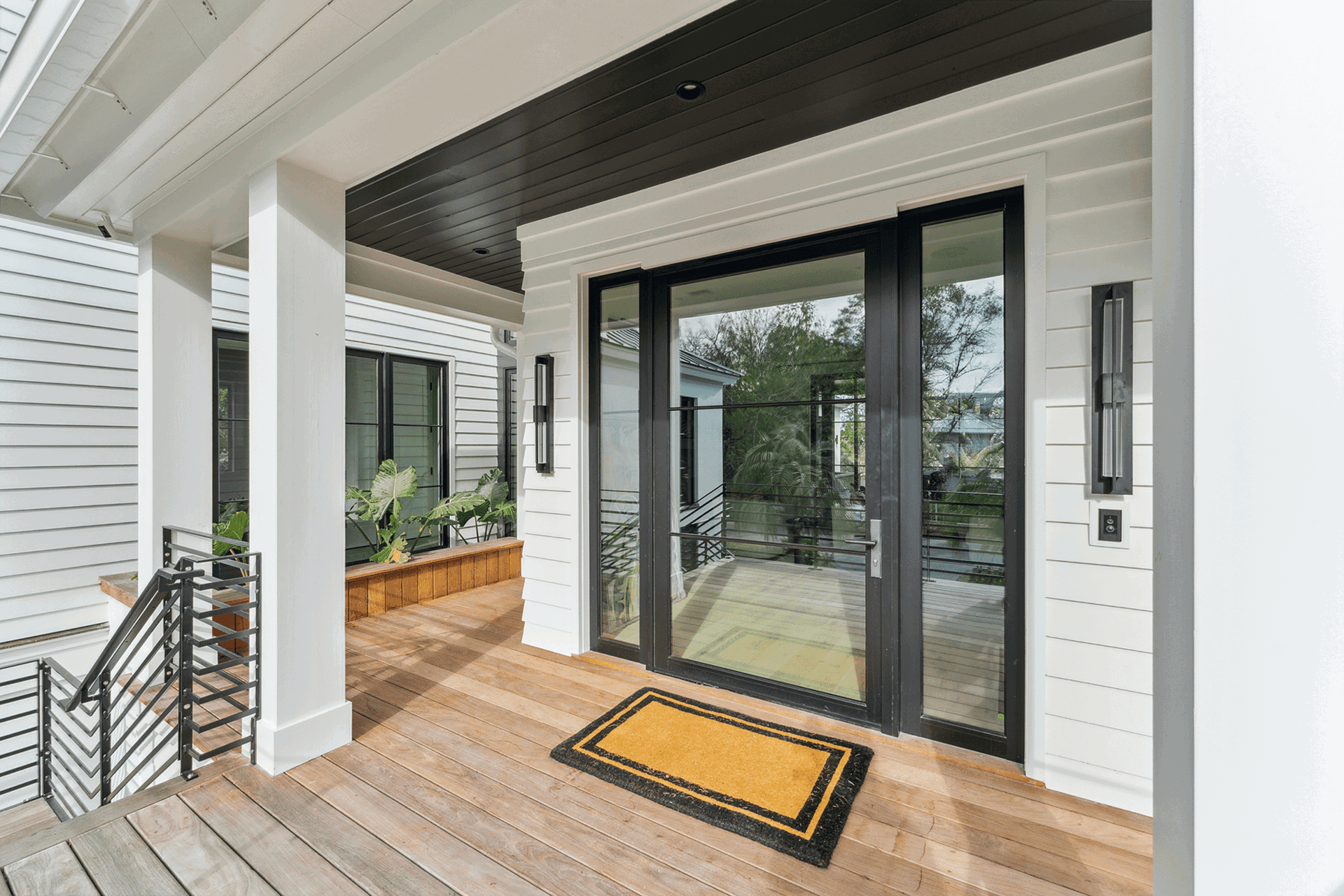 Modern back porch entrance featuring large sliding glass doors and coastal-inspired exterior design.